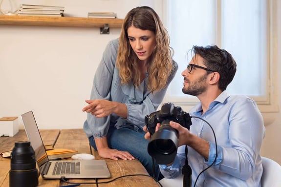 Valokuvaaja näyttää assistentilleen kuvia kannettavasta tietokoneesta.